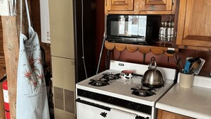 A kitchen with a white stove, wooden cabinets, a hanging pot, and a bag on the wall. - Dream Cabin in charming Hyde Park with WiFi access (HYDE PARK)