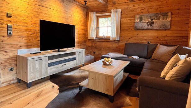 Interior acogedor de una cabaña con detalles de madera, un televisor de pantalla plana, un sofá y una mesa de comedor.