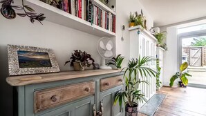 Une pièce avec un meuble en bois, une bibliothèque et une plante en pot.