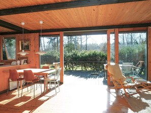 Un intérieur en bois comprenant un coin repas, une cuisine et une vue sur l’extérieur.