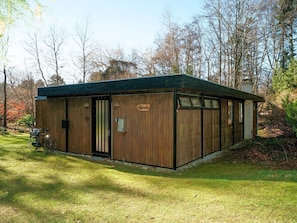 Une cabane en bois avec une pancarte indiquant « Chalet », située dans une zone boisée.