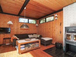 Un salon chaleureux avec des murs en bois, un canapé, une table basse, une cheminée et un téléviseur.