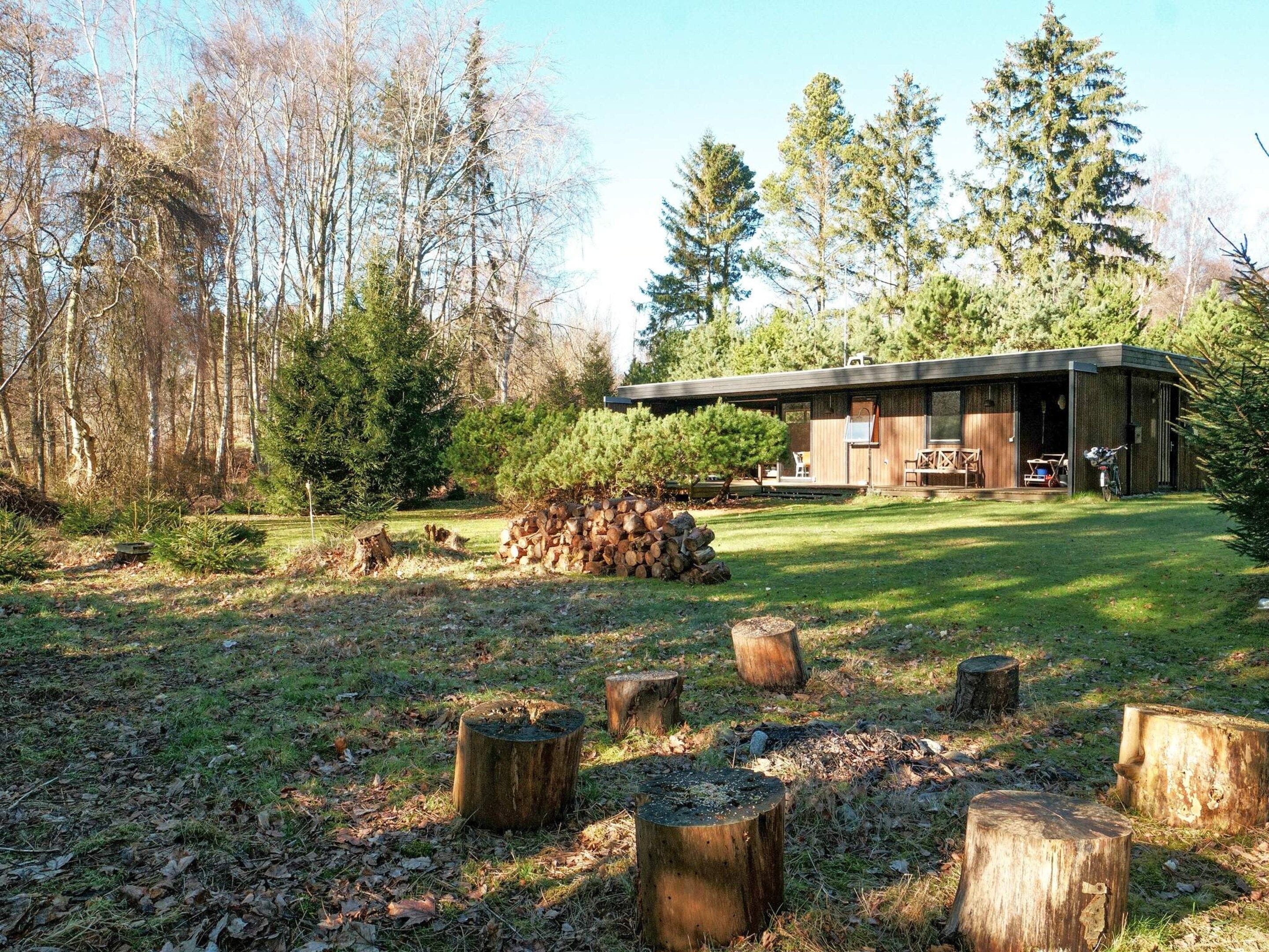 A cabin with a deck, surrounded by a forest.