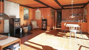 Un intérieur de chalet chaleureux avec une cheminée, des murs en bois, un coin repas et une cuisine.
