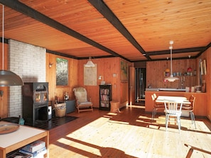 Un intérieur de chalet chaleureux avec une cheminée, des murs en bois, un coin repas et une cuisine.