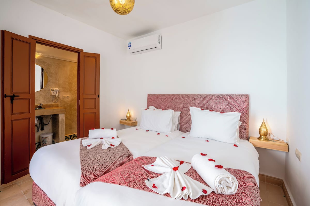 Habitación de hotel con una cama grande, un armario de madera, un baño pequeño y un aire acondicionado instalado en la pared.