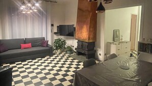 Una sala de estar moderna con piso a cuadros, un sofá, una mesa de comedor con sillas e iluminación colgante.
