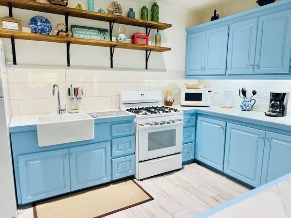 Una cocina con armarios azules, una estufa blanca y un microondas.