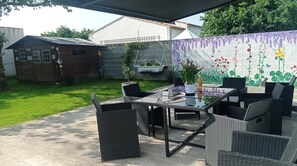 An outdoor patio with wicker furniture, a glass table, and a decorative wall mural. - Quiet house on the island of Oleron (Dolus-d'Oléron)