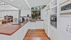 Una cucina moderna con mobili bianchi, un piano di lavoro in legno ed elettrodomestici integrati.