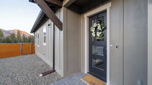 Une maison avec une porte d’entrée sombre, une clôture en bois et une allée gravillonnée.