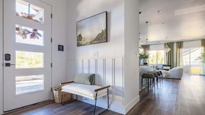 Un intérieur moderne avec un plancher en bois, un banc agrémenté de coussins, un tableau et une vue sur l’extérieur grâce à de grandes fenêtres.