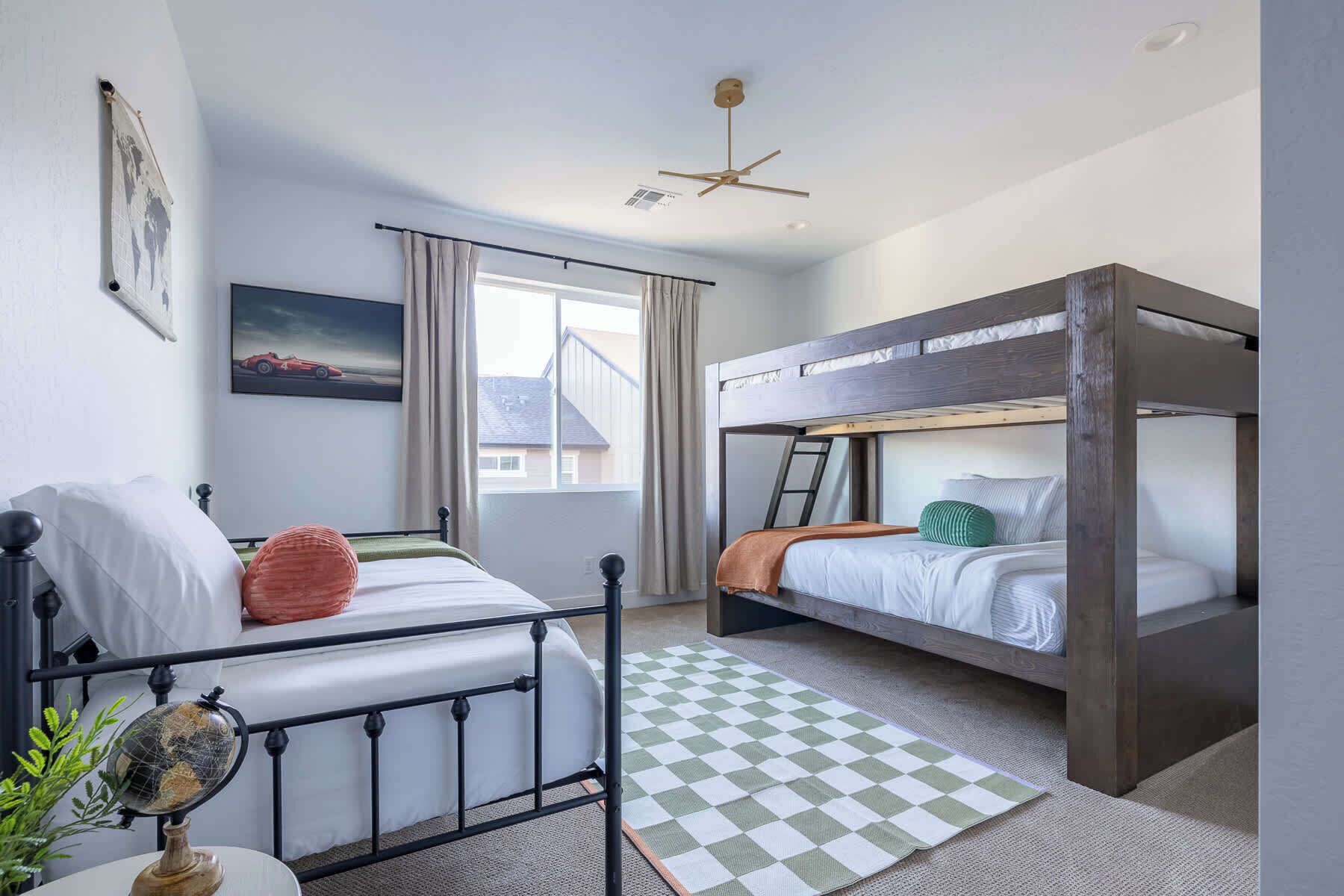 Ein Zimmer mit einem Etagenbett, einem Einzelbett, einem Globus auf einem Tisch und einem karierten Teppich.