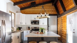 A modern kitchen with a large island, stainless steel appliances, and wooden beams. - Spacious 4BR Cabin with a Hot Tub (Munds Park)