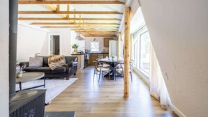 Amplia sala de estar con techo alto, vigas de madera, una mesa de comedor y una zona de estar acogedora.