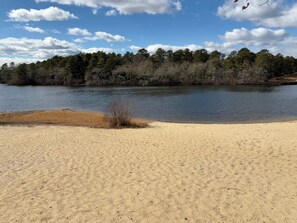 A sandy beach with a forest in the background and a clear sky. - Make this charming, modern retreat your home away from home!! (Wareham)