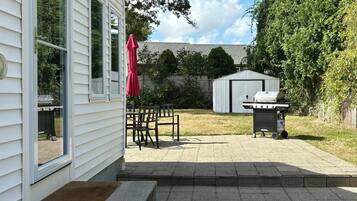 Ein Garten mit Terrasse, Grill und Geräteschuppen.