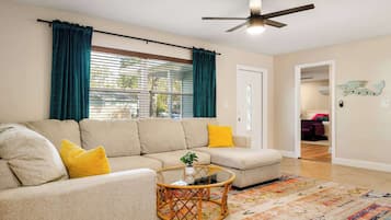A living room with a beige sectional sofa, a round coffee table, and a colorful rug.