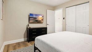 A bedroom with a bed, a dresser, a painting, and a closet.