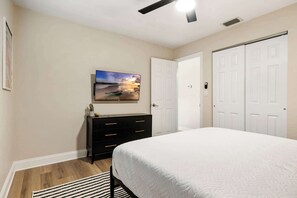 A bedroom with a bed, a dresser, a painting, and a closet.