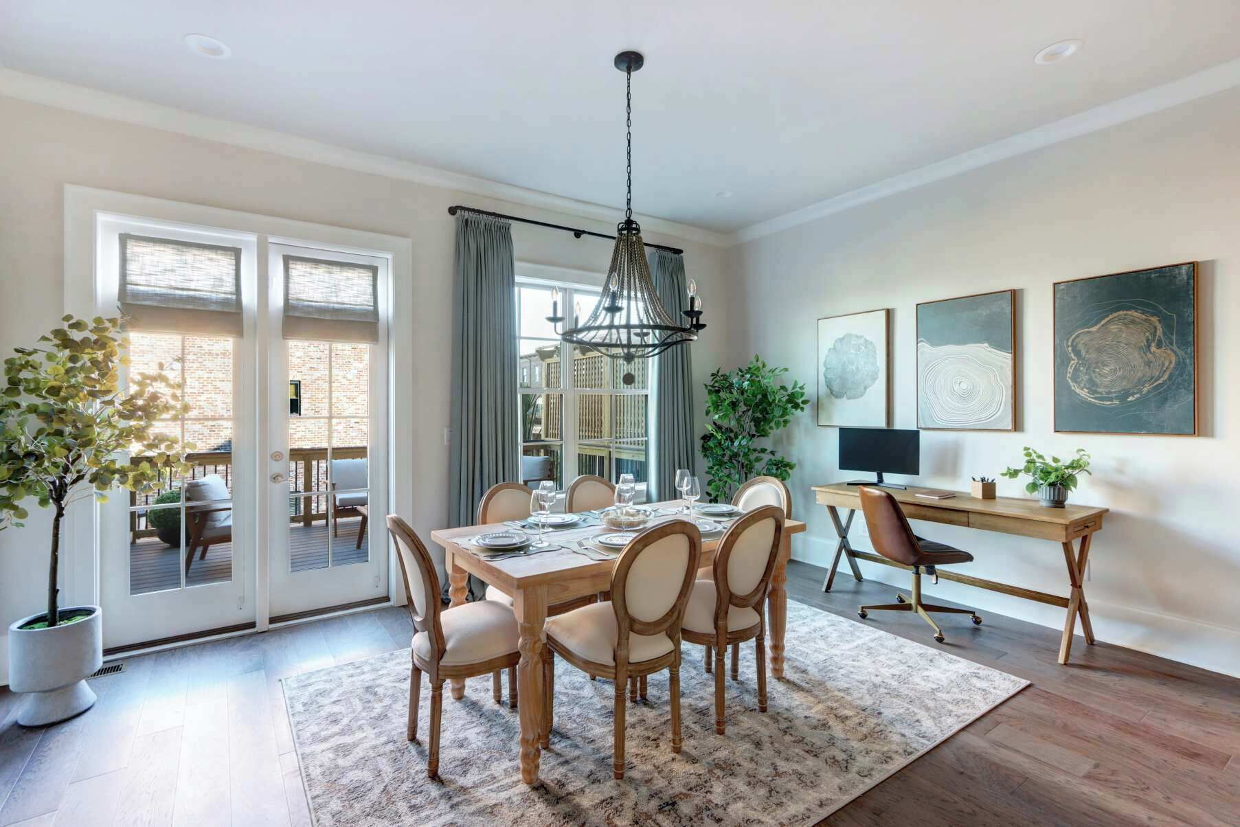 A dining area with a wooden table and chairs, a hanging light fixture, and artwork on the wall.