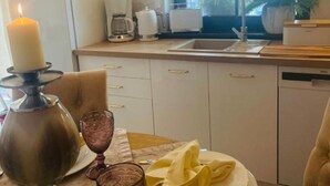 A cozy kitchen with a dining table set for two, featuring a candle, a glass, and plates. - Holiday Home With Sauna and Whirlpool (Międzyzdroje)