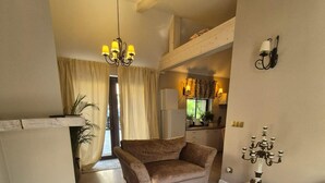 A spacious living room with a sofa, ottoman, and a small table with a decorative item. A kitchen is visible in the background. - Holiday Home With Sauna and Whirlpool (Międzyzdroje)
