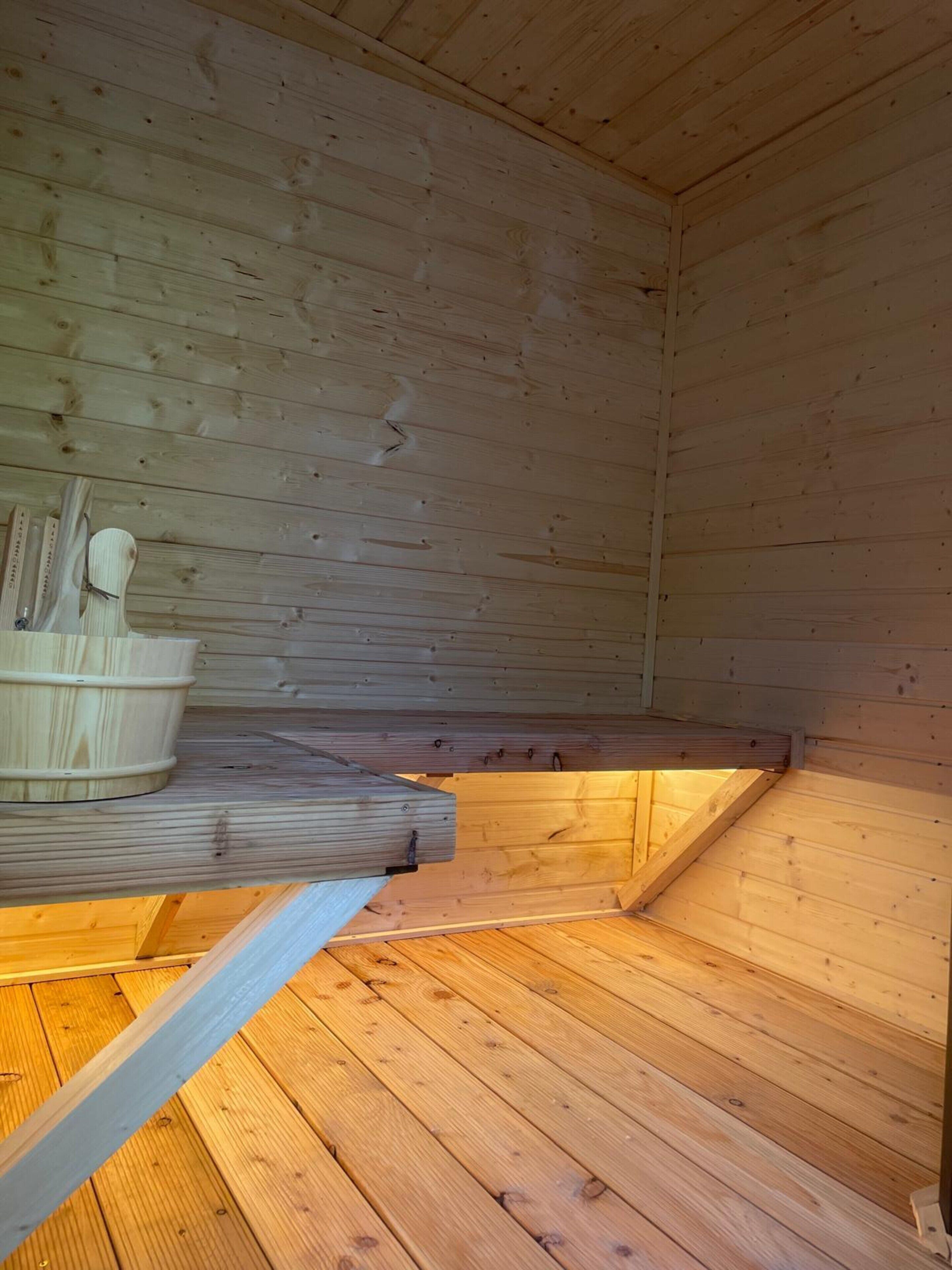 A wooden cabin interior with a built-in bench and a small wooden table.