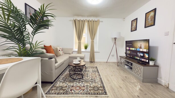 A living room with a sofa, coffee table, TV, and a large plant.
