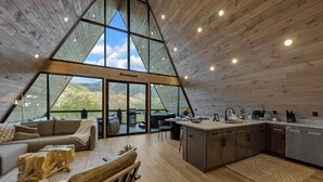A modern loft-style interior with a kitchen, dining area, and living space. - NEW Modern A-Frame w/Hot Tub! (Sevierville)