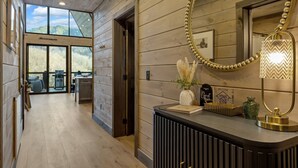 A modern hotel lobby with wooden paneling, a reception desk, a large mirror, and a view of the outdoors. - NEW Modern A-Frame w/Hot Tub! (Sevierville)