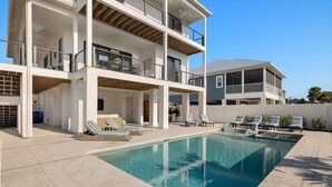 A modern multi-story house with a swimming pool and outdoor seating. - Villa Capri · 2025 Luxury Build · Steps to Beach (Fort Myers Beach)