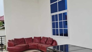 A corner room with a red leather sofa, a glass-top table, and a large window. - King George Lodge  (Tema)