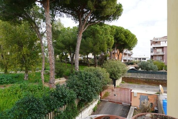 A residential area with trees, a gated driveway, and apartment buildings in the background.