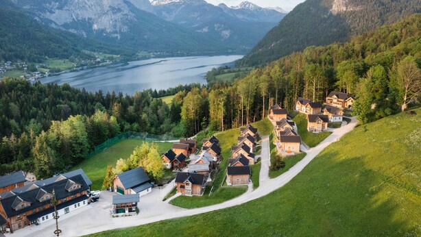Un conjunto de casas de madera con montañas al fondo y un lago.