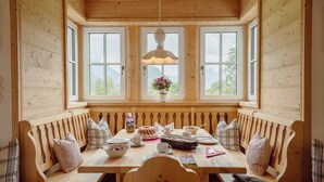 Un comedor de madera con banco, mesa y lámpara colgante.