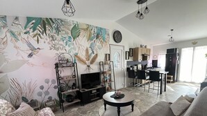 A living room with a large mural, a television, a coffee table, and a sofa. - WELCOME TO "LOU PARADOU" NEW HOUSE FOR 4 PEOPLE IN PROVENCE VERTE (Méounes-lès-Montrieux)