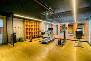 Ein Fitnessraum mit Trainingsgeräten, Holzboden und Ziegelwänden.