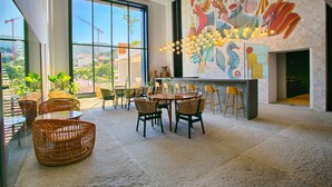 Un'ampia sala da pranzo con mobili in vimini, ampie finestre e un affresco sulla parete.