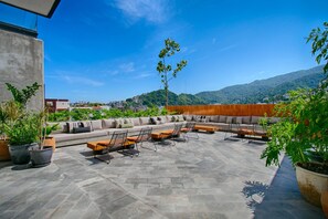 Eine Dachterrasse mit einer Sitzecke, Stühlen und Topfpflanzen.