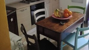 Keittiössä on vaaleista puulankuista tehdyt kaapit, kaasuliesi ja ruokapöytä tuoleineen. Seinällä on kehystettyjä tauluja.