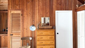 Ein Holzblockhaus-Innenraum mit Schlafgalerie, einem Holzkasten, einem Sessel und einer Lampe.
