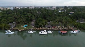 Ein Yachthafen mit mehreren dort festgemachten Booten, umgeben von dichter Vegetation und kleinen Gebäuden mit Strohdächern.