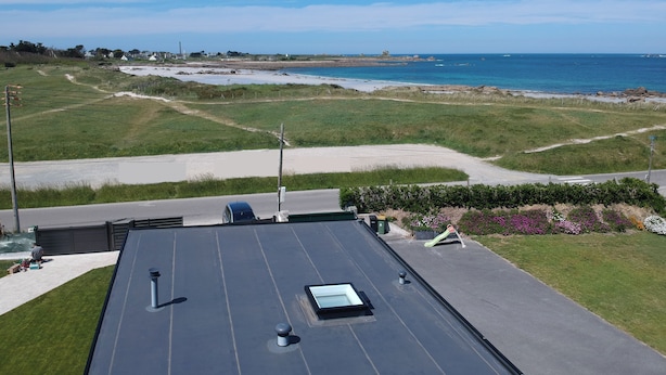 A rooftop with a skylight, a view of a beach, and a clear sky. - Recent house facing the dunes and Grève Blanche beach, at the foot of the GR34. (Plouguerneau)