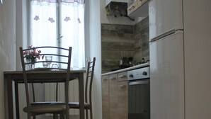 A kitchen with a dining table and chairs, a refrigerator, and a stove. - Tre Cuori - Amy. (Genova)