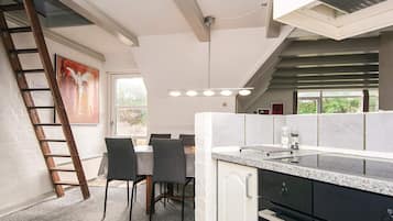 Una cocina con mostrador, sillas, escalera y ventana.