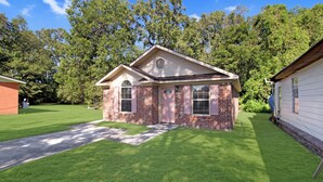 A small brick house with a front porch, a well-maintained lawn, and a garage.