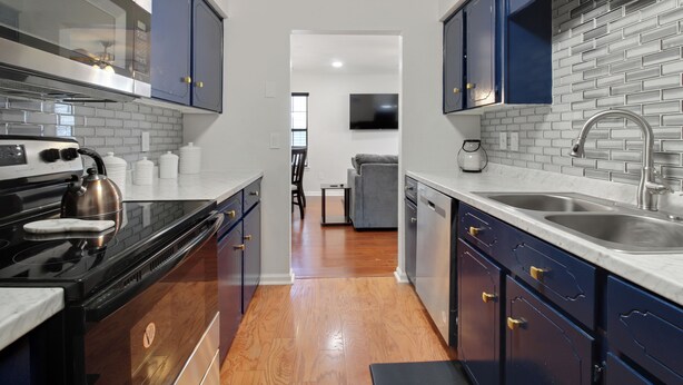 A modern kitchen with stainless steel appliances, blue cabinets, and a tiled backsplash.