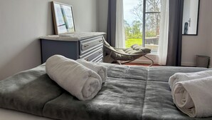 A bedroom with a bed, a bedside table with a picture, a window with curtains, and a chair. - Biscoitos Top View apartment overlooking the sea with AC and very fast Wi-Fi (Biscoitos)