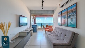 A modern living room with a sofa, a TV, and artwork on the wall.